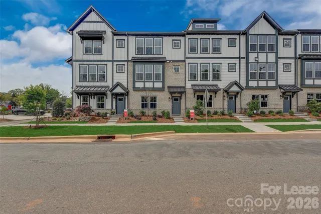 a front view of an apartment building with yard and green space