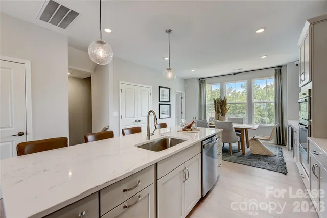 a kitchen with stainless steel appliances granite countertop a stove a refrigerator a kitchen island a table and chairs