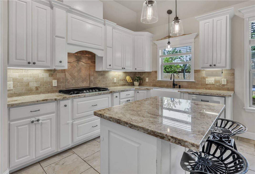 8312 Raintree Drive College Station, TX 77845 - Photo 11 of 30 White cabinetry with under-cabinet lighting, natural stone countertops, a tile backsplash, and a gas cooktop