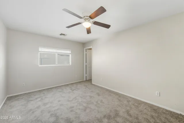 an empty room with ceiling fan and window