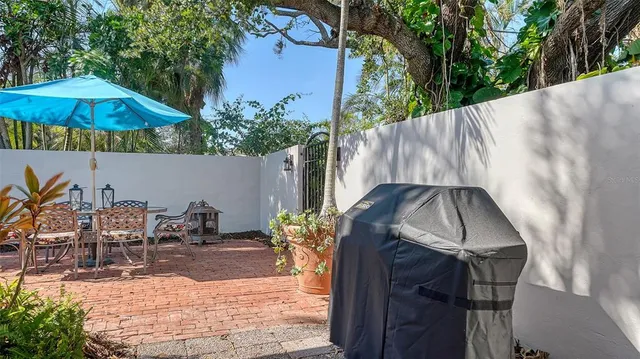 a backyard of a house with table and chairs under an umbrella