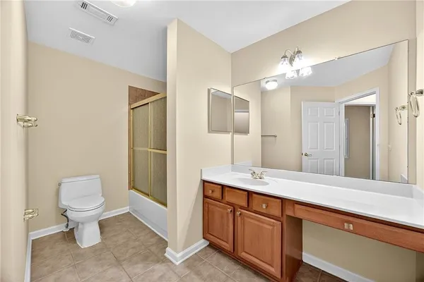 a spacious bathroom with a granite countertop toilet a sink and a mirror