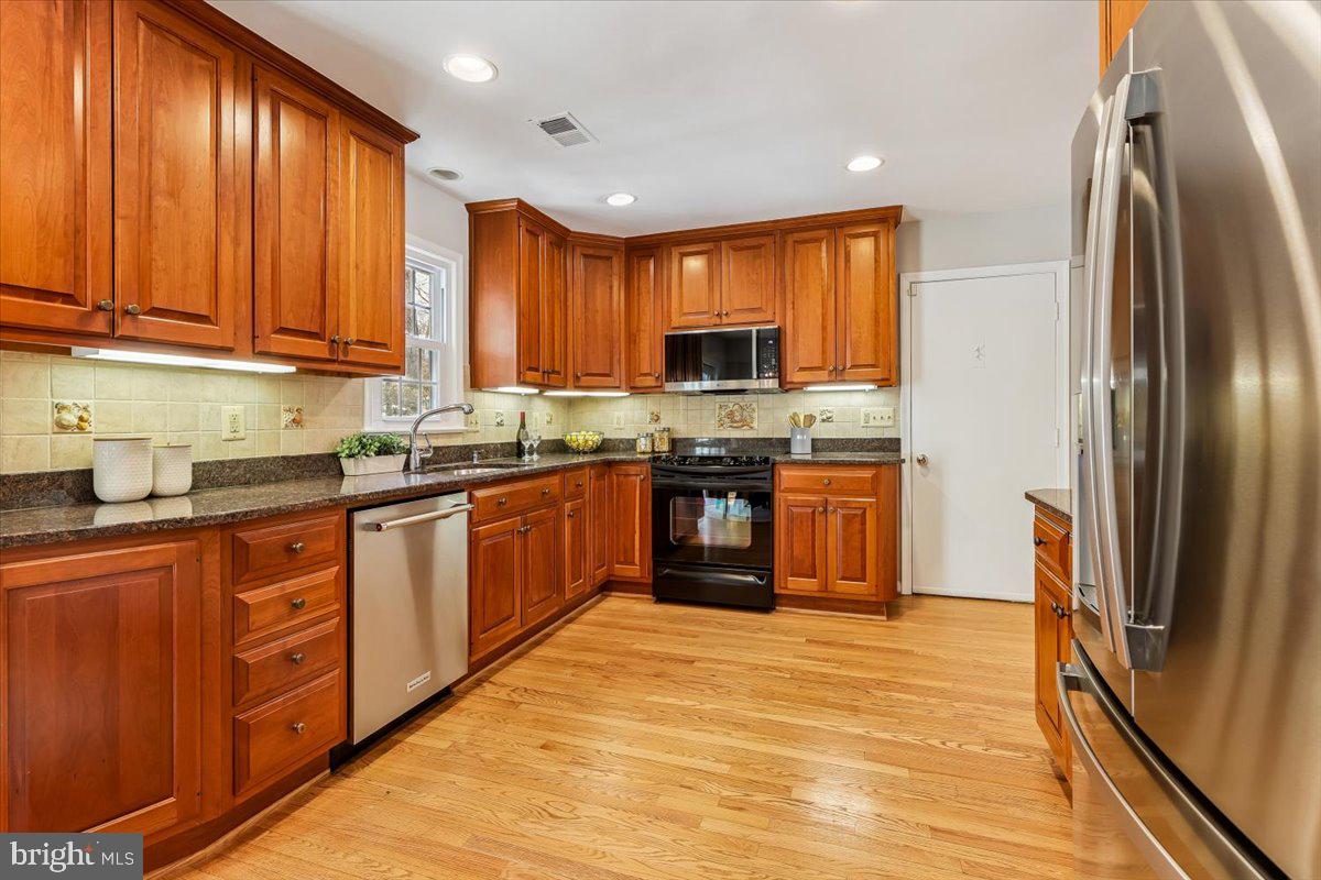 3105 Miller Heights Road Oakton, VA 22124 - Photo 3 of 60 a kitchen with stainless steel appliances granite countertop a refrigerator a sink dishwasher a stove with wooden cabinets and floor
