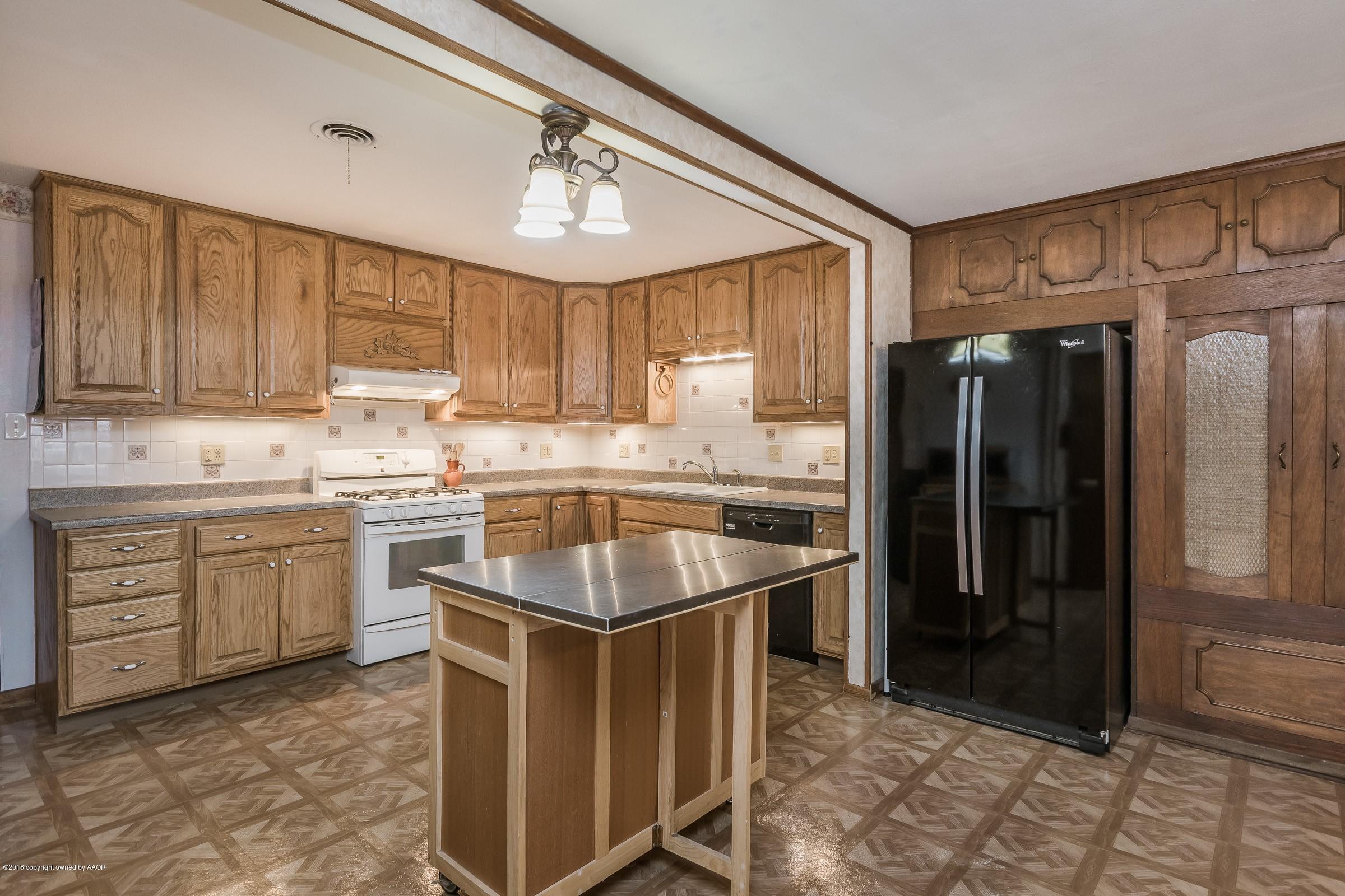 1201 Southwest 48th Avenue Amarillo, TX 79110 - Photo 4 of 18 a kitchen with stainless steel appliances granite countertop a sink a stove a refrigerator cabinets and a window