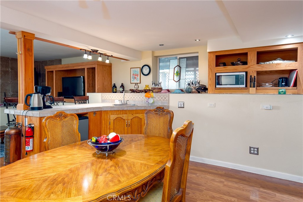 10960 Steinhoff Road Frazier Park, CA 93225 - Photo 40 of 46 A view of the functional kitchen and dining space located inside the private downstairs suite. This area features continuous wood flooring, a cozy dining setup, a raised breakfast bar counter, and warm oak upper and lower cabinetry with integrated appliances, perfect for independent guest living or rental potential.