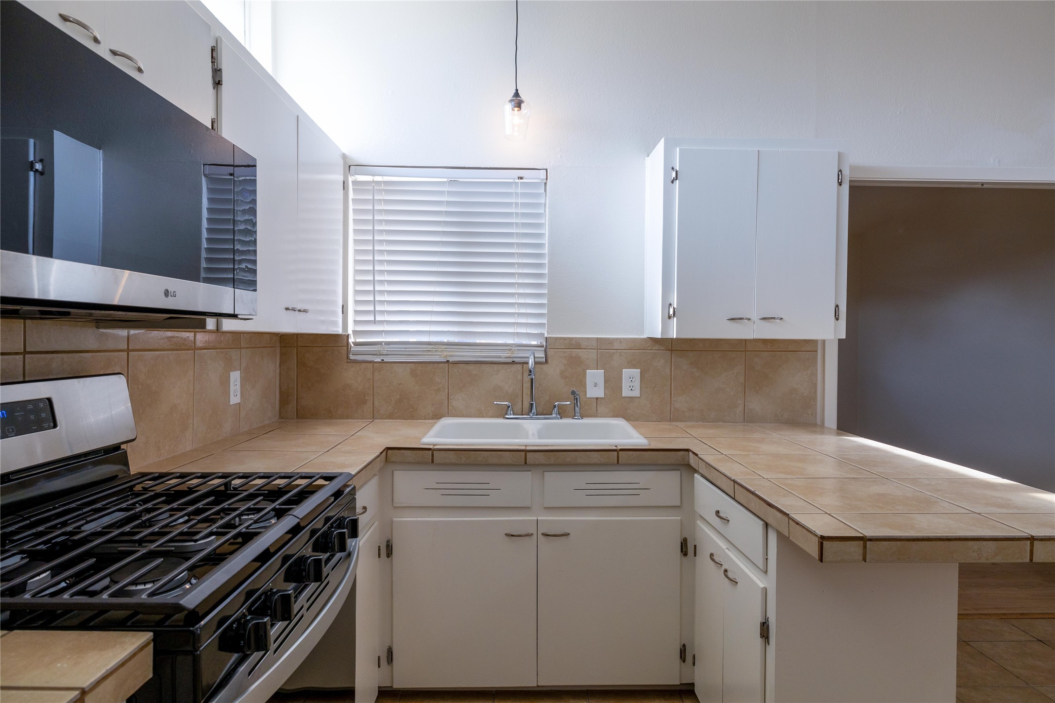 4304 Scottsdale Road Austin, TX 78721 - Photo 5 of 18 Kitchen featuring stainless steel appliances, a peninsula, white cabinets, and backsplash