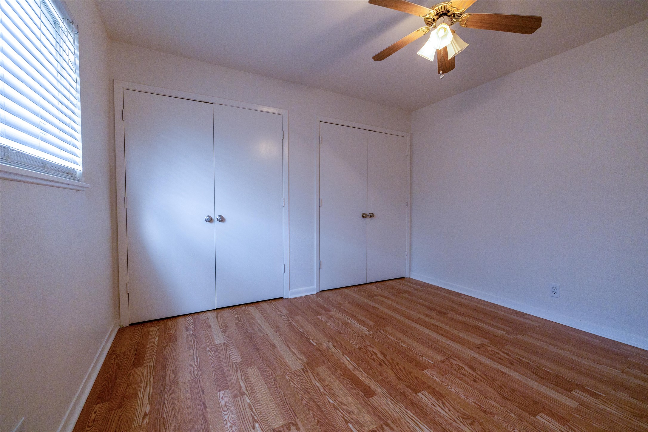 4304 Scottsdale Road Austin, TX 78721 - Photo 8 of 18 Unfurnished bedroom with two closets, light wood finished floors, and ceiling fan