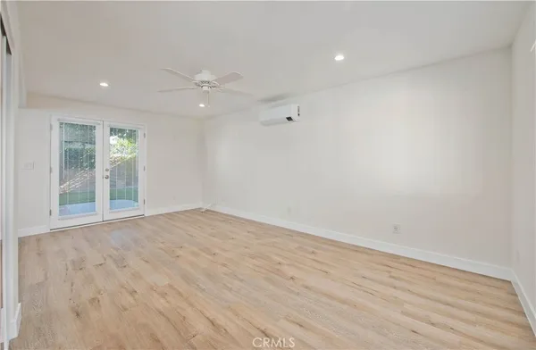 a view of an empty room with wooden floor and a ceiling fan