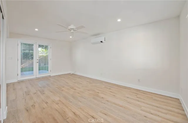 a view of an empty room with wooden floor and a ceiling fan