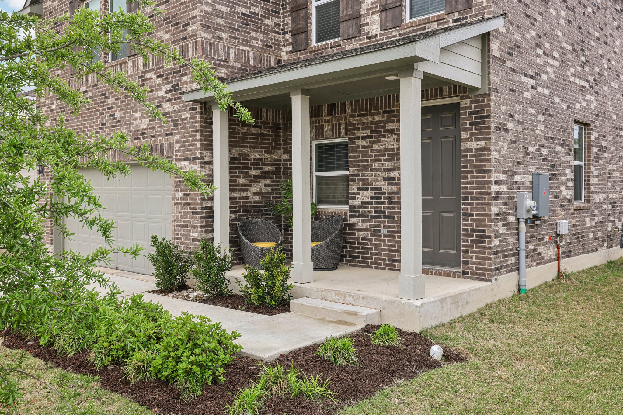 204 Swinging H Lane Georgetown, TX 78633 - Photo 4 of 39 The property features a brick exterior, a covered porch entry, and an attached garage with a light-colored door