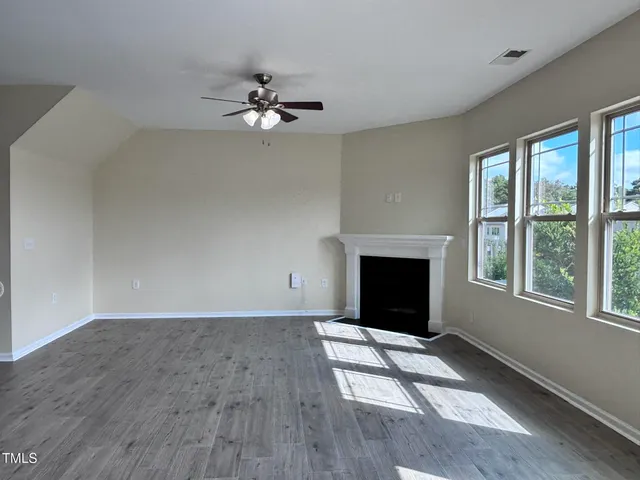 wooden floor fireplace and windows in an empty room