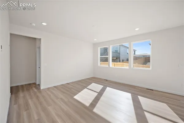 a view of an empty room with a window and wooden floor