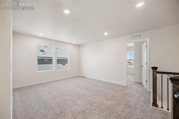 an empty room with chandelier fan and windows