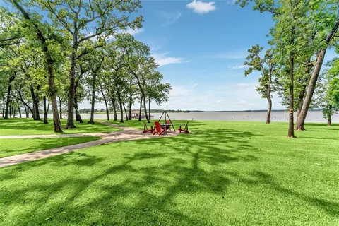 a view of grassy field with benches and trees all around