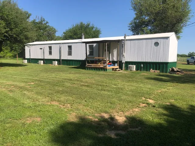 a view of a lake with a yard and large trees