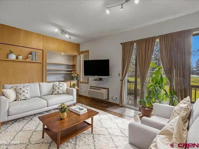 a living room with furniture a flat screen tv and a large window
