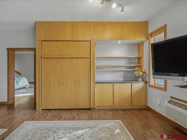 a view of an empty room with wooden floor and a cabinet