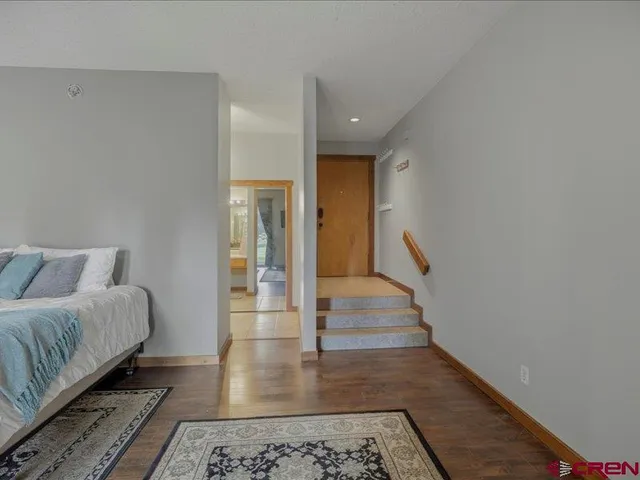 a spacious bedroom with a bed and wooden floor