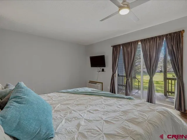 a bedroom with a bed and a flat tv screen next to a large window