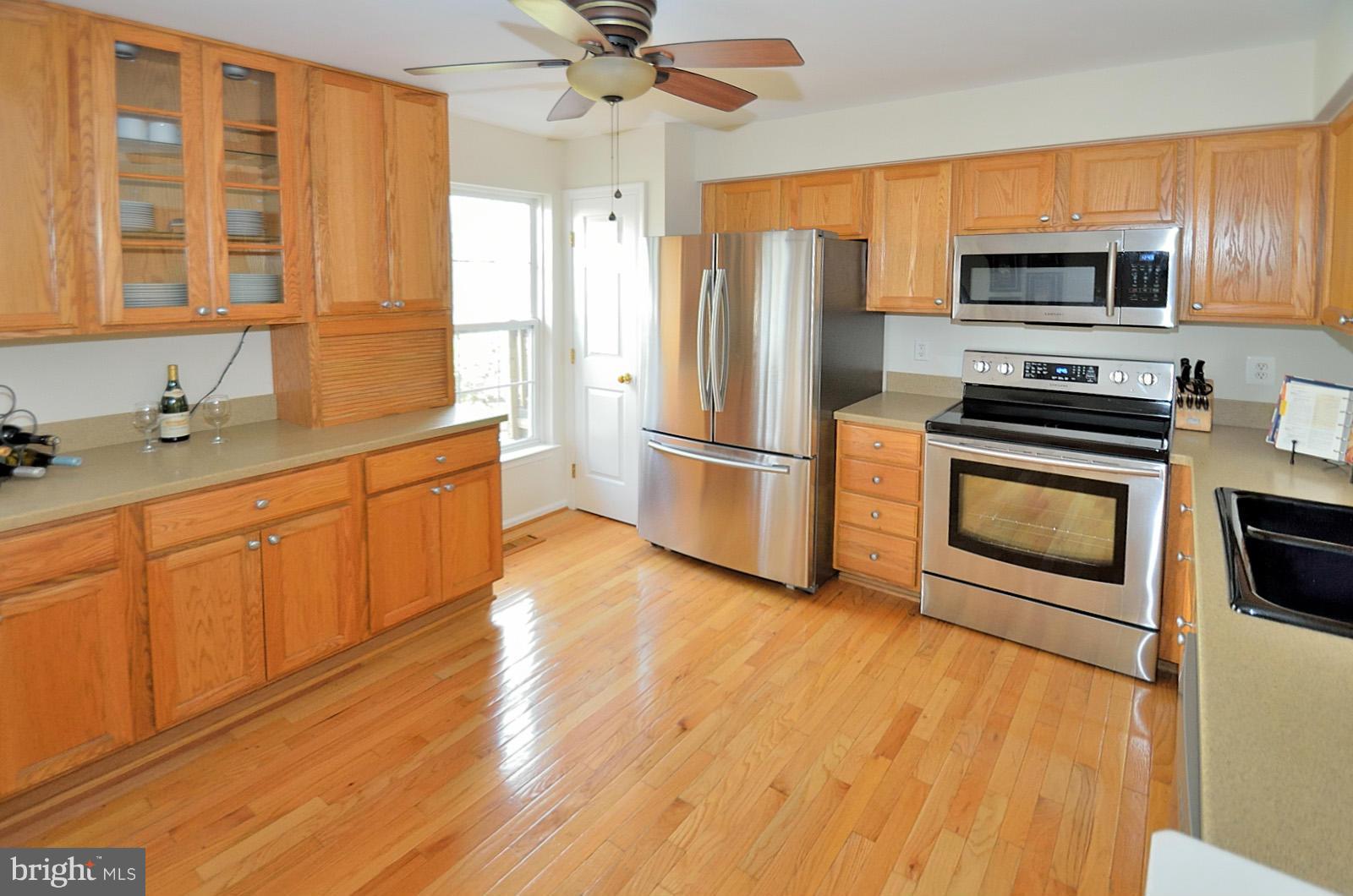 19933 Ridgecrest Square Ashburn, VA 20147 - Photo 4 of 19 a kitchen with wooden floors and stainless steel appliances