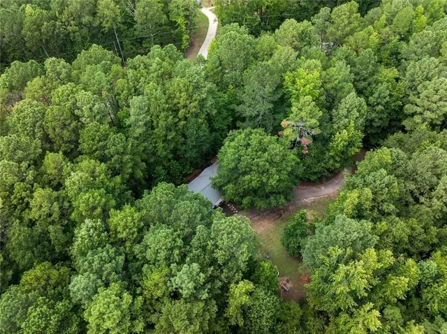an aerial view of residential house with outdoor space and trees all around