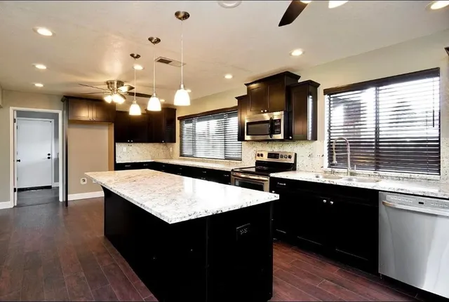 a large kitchen with granite countertop a sink and cabinets