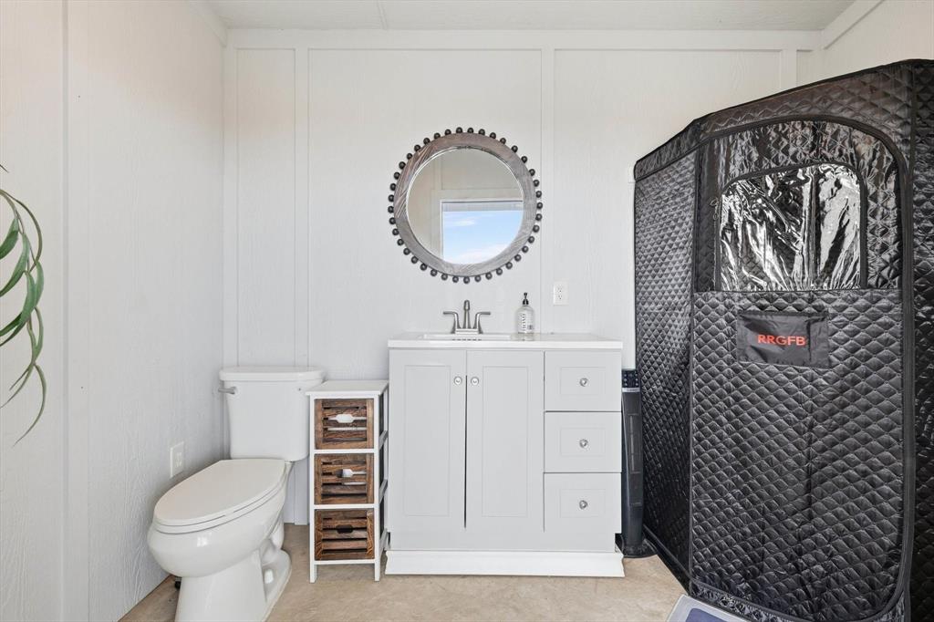 7751 Faught Road Northlake, TX 76226 - Photo 30 of 39 Bathroom featuring a vanity with a white countertop and gray cabinetry, a wall-mounted circular mirror, and board-and-batten style wall paneling