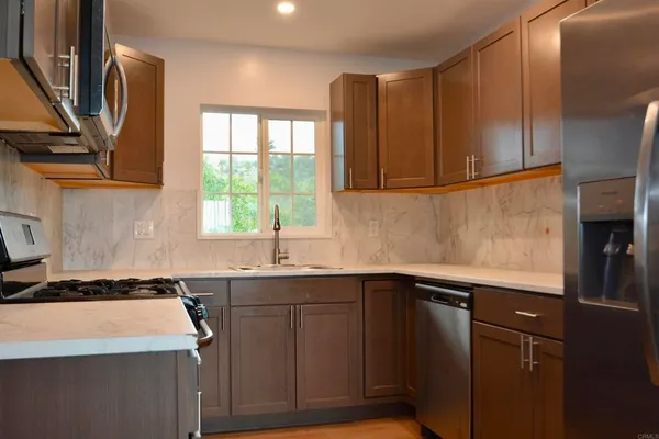 a kitchen with granite countertop a refrigerator and a stove top oven