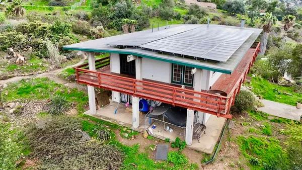 an aerial view of a house with pool and trees in the background