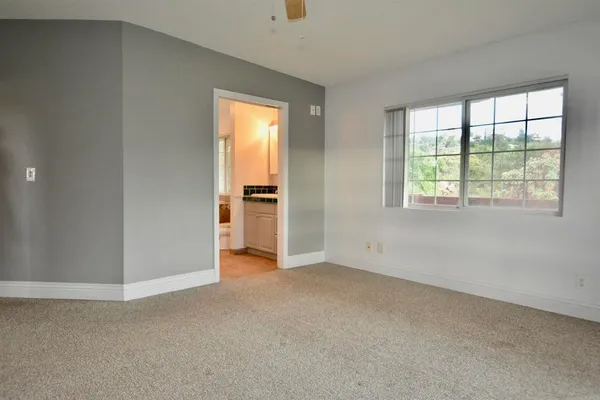 an empty room with windows and fan