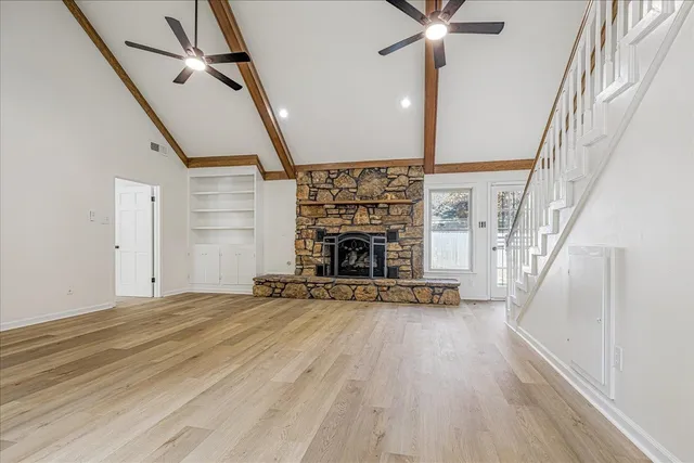 a view of an empty room with wooden floor fireplace and a window