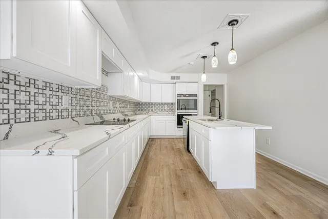 a kitchen with kitchen island a counter top space a sink stainless steel appliances and cabinets