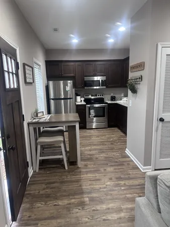 a kitchen with stainless steel appliances wooden floor and a refrigerator