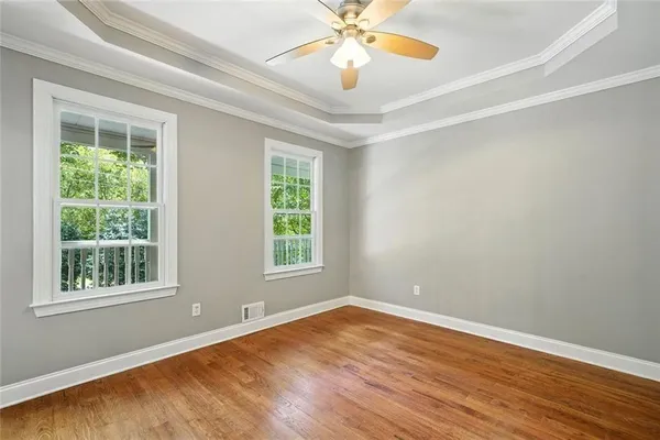 an empty room with wooden floor chandelier fan and windows