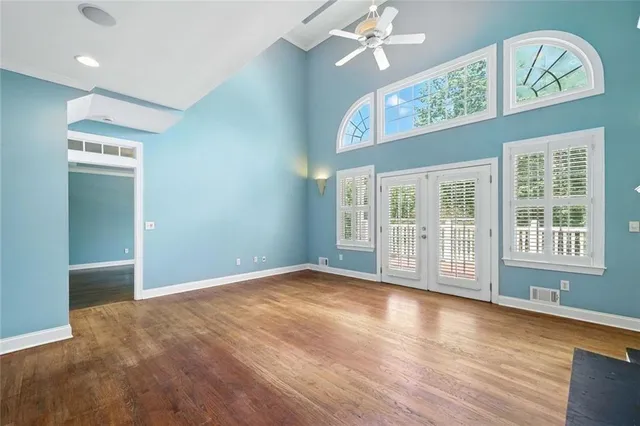 an empty room with wooden floor and windows