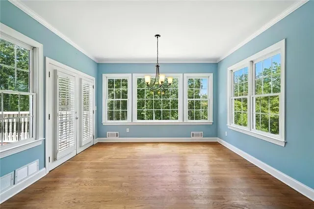 an empty room with chandelier fan and windows