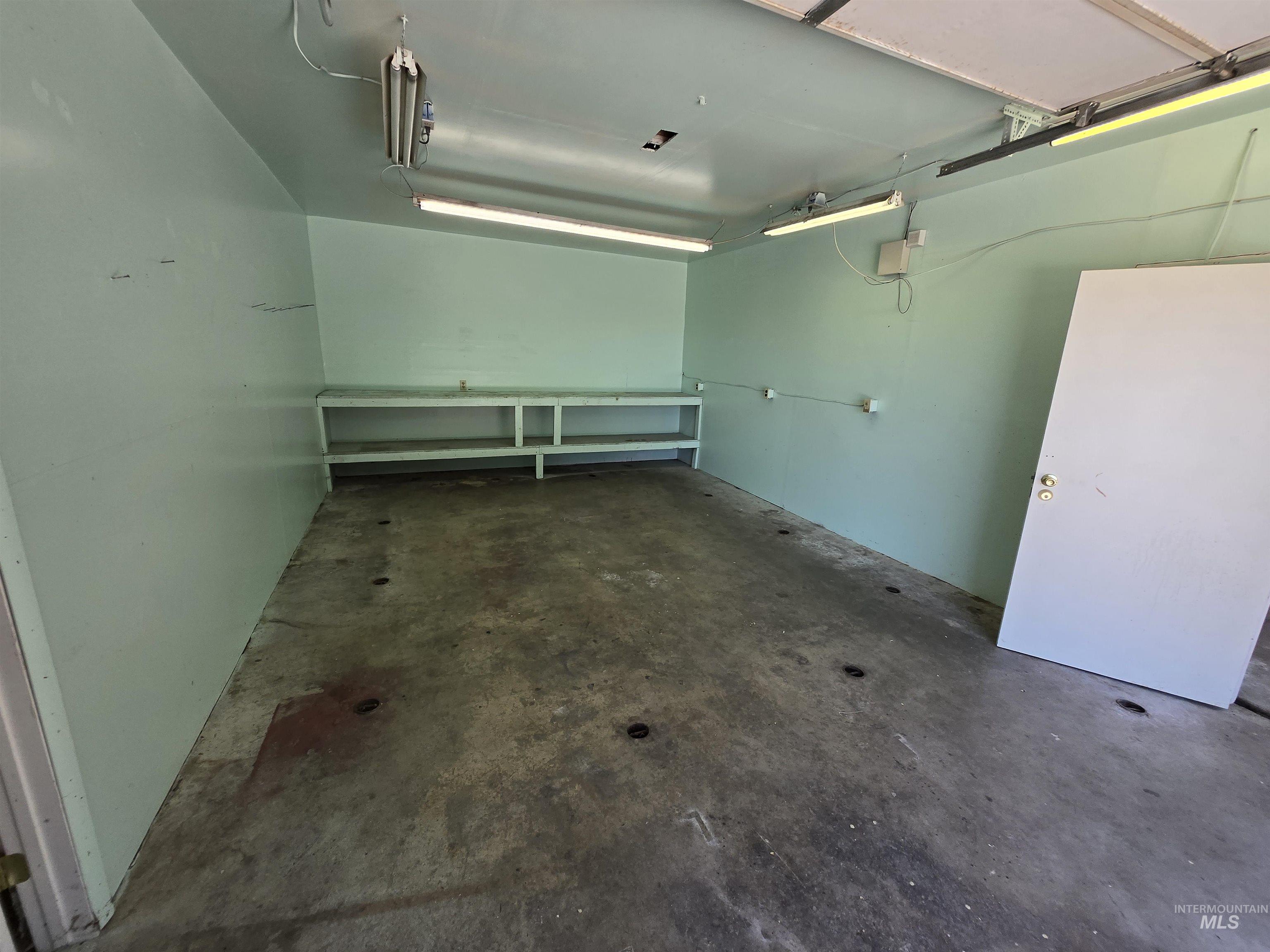 12050 West Hidden Valley Rim Road Boise, ID 83709 - Photo 29 of 39 Spacious garage featuring a concrete floor, built-in shelving, white walls, and multiple fluorescent light fixtures