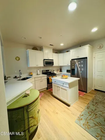 a kitchen with stainless steel appliances kitchen island granite countertop a sink refrigerator and cabinets