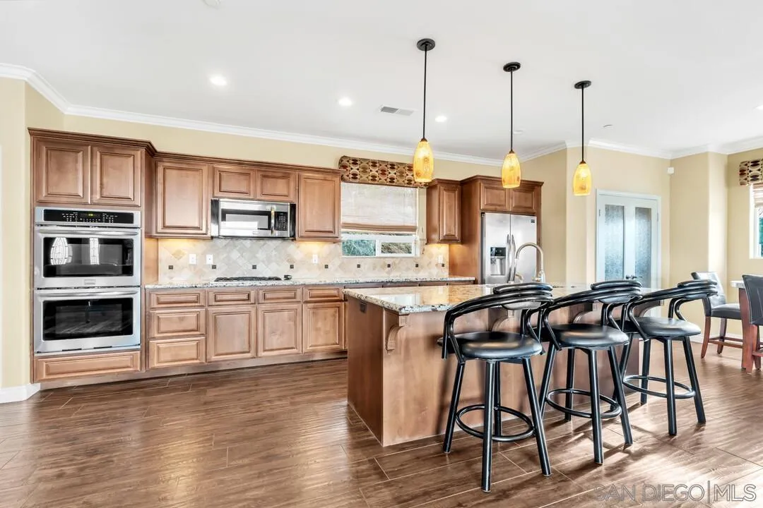 352 Sneath Way Alpine, CA 91901 - Photo 12 of 50 a kitchen with stainless steel appliances granite countertop a stove top oven a sink a dining table and chairs with wooden floor