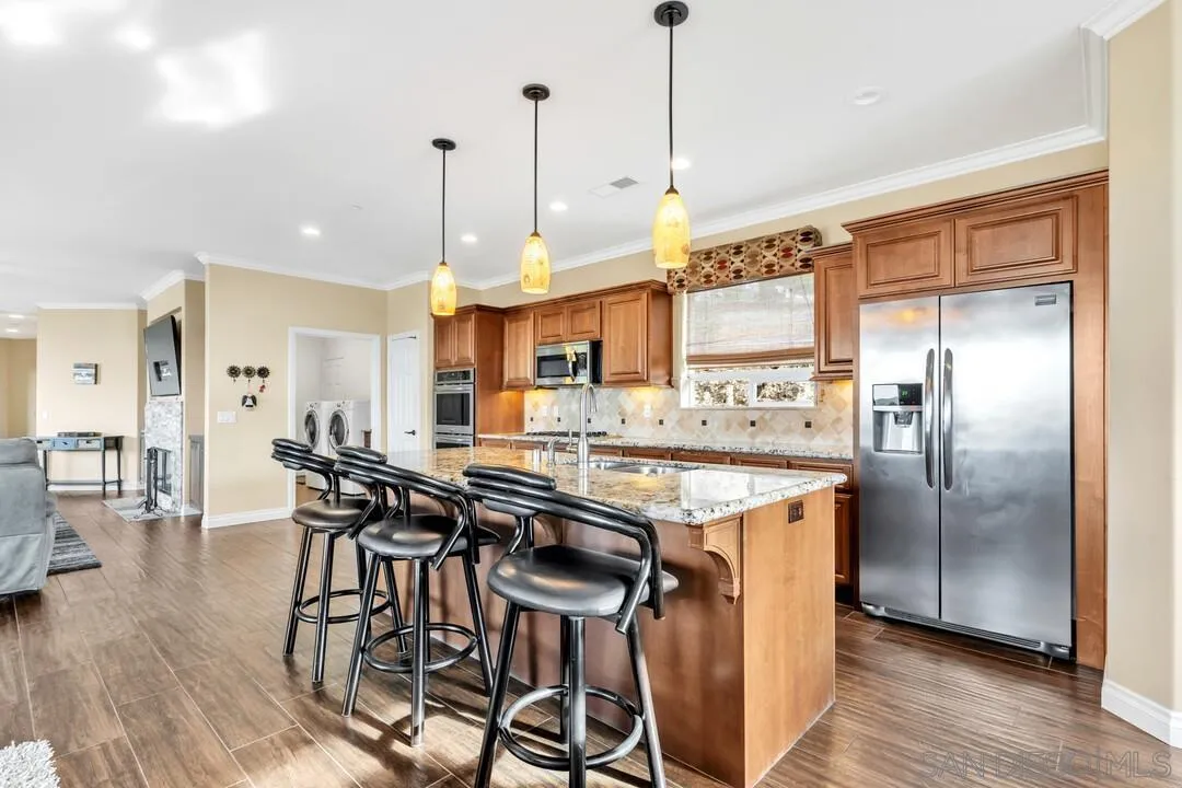 352 Sneath Way Alpine, CA 91901 - Photo 13 of 50 a kitchen with stainless steel appliances granite countertop a table chairs stove and wooden floor