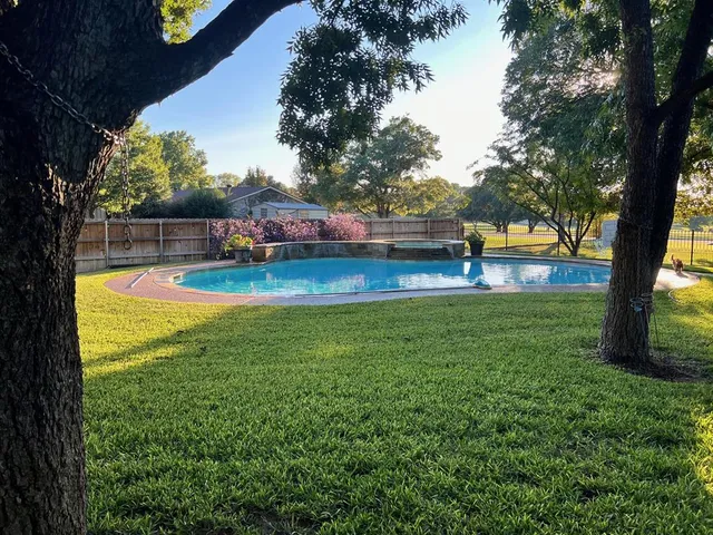 a view of a swimming pool with a patio and a yard