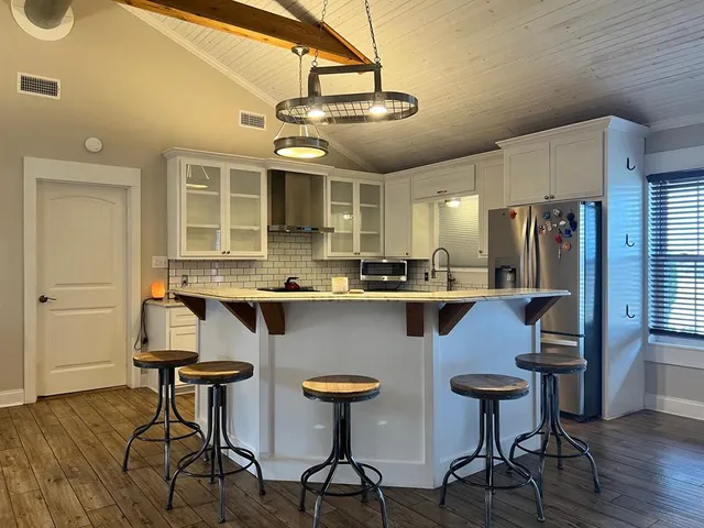 a kitchen with stainless steel appliances granite countertop a table chairs refrigerator and cabinets