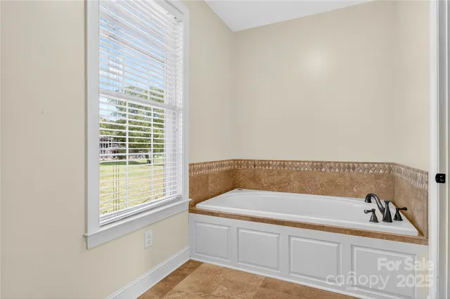 a bathroom with bathtub next to a window