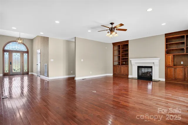 a view of a livingroom with a fireplace a ceiling fan and windows