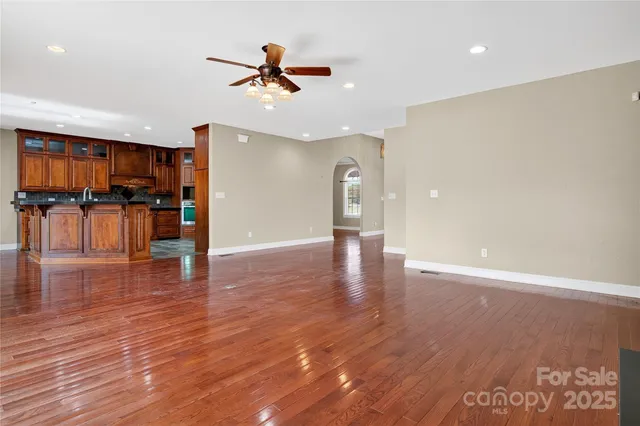 a view of empty room with wooden floor and ceiling fan
