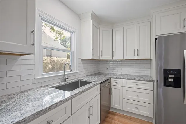 a kitchen with granite countertop a sink stainless steel appliances and cabinets