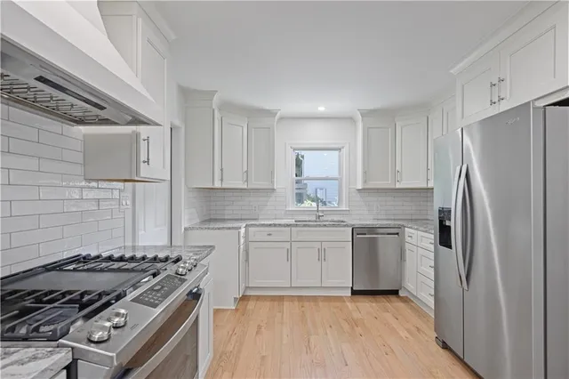 a kitchen with stainless steel appliances granite countertop a stove a refrigerator and a sink