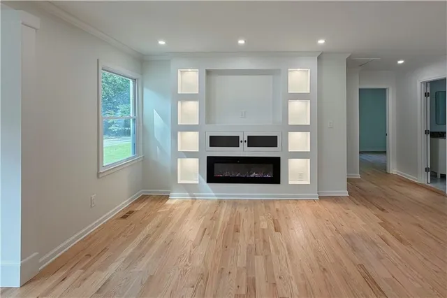 an empty room with wooden floor fireplace and windows
