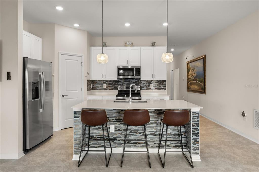 287 Inman Boulevard Winter Haven, FL 33881 - Photo 11 of 36 a kitchen with kitchen island a dining table and a refrigerator