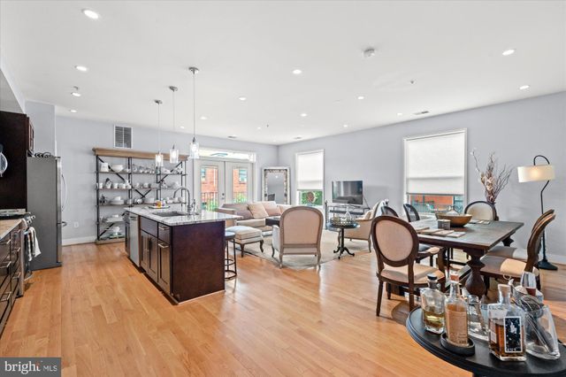 a living room with stainless steel appliances furniture a rug and a kitchen view